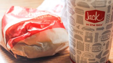 WASHINGTON, ABD - 15 Mart 2022 Hamburgerdeki Jack, kahverengi ahşap bir masada servis edilen patates kızartması ve bardaklar.