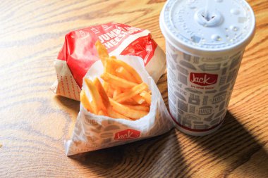 WASHINGTON, ABD - 15 Mart 2022 Hamburgerdeki Jack, kahverengi ahşap bir masada servis edilen patates kızartması ve bardaklar.