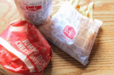 WASHINGTON, ABD - 15 Mart 2022 Hamburgerdeki Jack, kahverengi ahşap bir masada servis edilen patates kızartması ve bardaklar.
