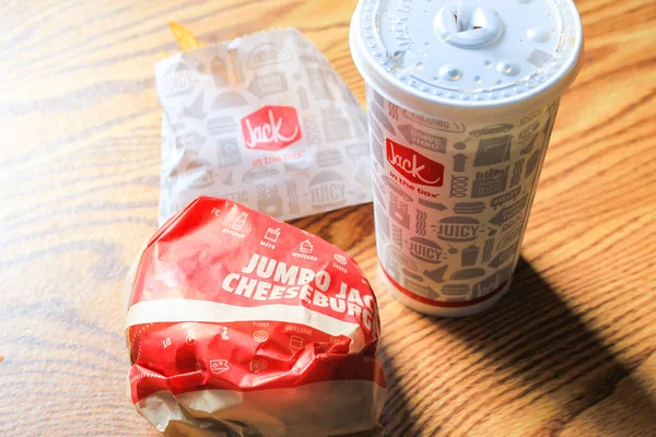 WASHINGTON, ABD - 15 Mart 2022 Hamburgerdeki Jack, kahverengi ahşap bir masada servis edilen patates kızartması ve bardaklar.