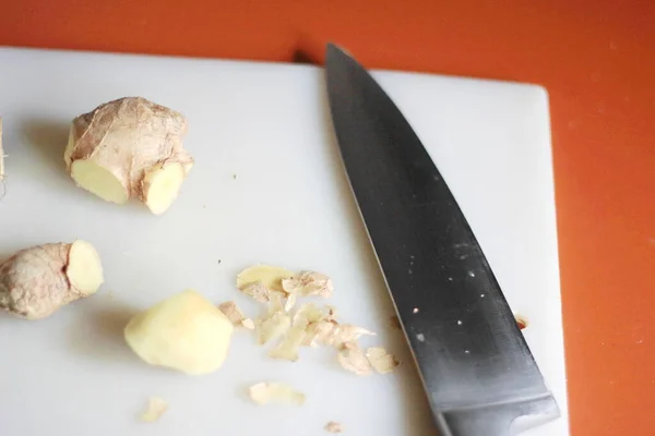 Ginger Turuncu Bir Masada Bıçakla Plastik Bir Doğrama Tahtasının Üzerinde — Stok fotoğraf