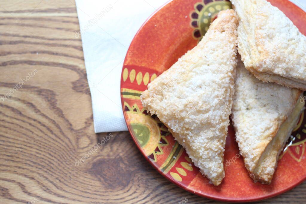 Turnovers Apple, Apple Pie, Served in an Orange Plate on brown wooden table, Turnovers Apple is a popular dish in America - Flat-Lay.