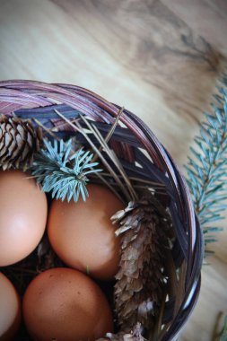 Çam dalları ve kozalaklarla dolu bir sepetin içinde paskalya yumurtaları..