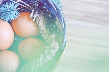 Çam dalları ve kozalaklarla dolu bir sepetin içinde paskalya yumurtaları..