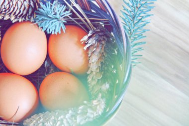 Çam dalları ve kozalaklarla dolu bir sepetin içinde paskalya yumurtaları..