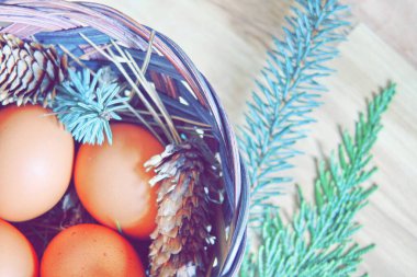 Çam dalları ve kozalaklarla dolu bir sepetin içinde paskalya yumurtaları..
