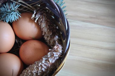 Çam dalları ve kozalaklarla dolu bir sepetin içinde paskalya yumurtaları..
