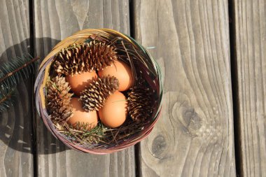 Dört kişilik bir sepetin içinde paskalya yumurtaları ve arka planda çam kozalakları..