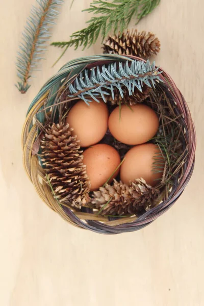 Dört kişilik bir sepetin içinde paskalya yumurtaları ve arka planda çam kozalakları..