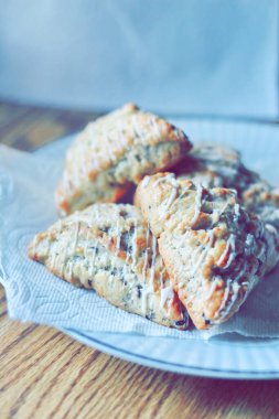 beyaz bir tabakta servis edilen yaban mersinli çörekler ahşap bir masada, modern tonlarda resmedilmiş..