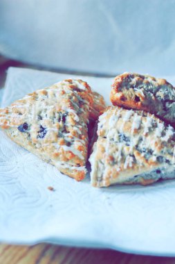 beyaz bir tabakta servis edilen yaban mersinli çörekler ahşap bir masada, modern tonlarda resmedilmiş..