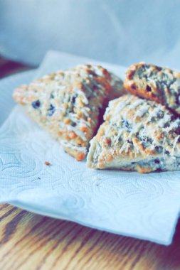 beyaz bir tabakta servis edilen yaban mersinli çörekler ahşap bir masada, modern tonlarda resmedilmiş..