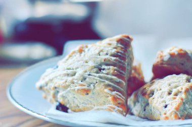 beyaz bir tabakta servis edilen yaban mersinli çörekler ahşap bir masada, modern tonlarda resmedilmiş..