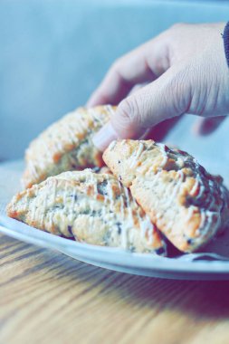 beyaz bir tabakta servis edilen yaban mersinli çörekler ahşap bir masada, modern tonlarda resmedilmiş..