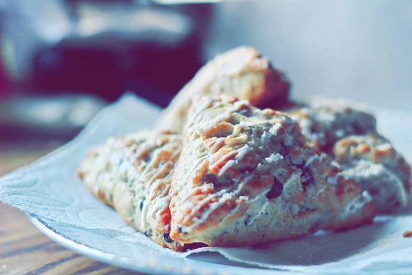 beyaz bir tabakta servis edilen yaban mersinli çörekler ahşap bir masada, modern tonlarda resmedilmiş..