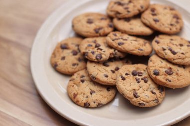 Çikolatalı kurabiyeler açık kahverengi bir tabakta hazırlanır ve çocuklara servis edilmeye hazırdır..