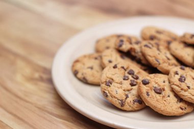 Çikolatalı kurabiyeler açık kahverengi bir tabakta hazırlanır ve çocuklara servis edilmeye hazırdır..