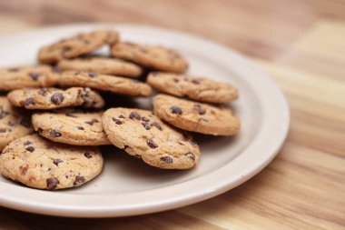 Çikolatalı kurabiyeler açık kahverengi bir tabakta hazırlanır ve çocuklara servis edilmeye hazırdır..