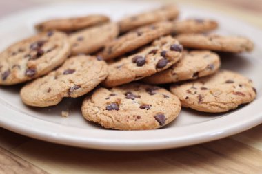 Çikolatalı kurabiyeler açık kahverengi bir tabakta hazırlanır ve çocuklara servis edilmeye hazırdır..