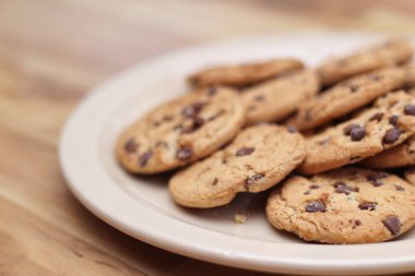 Çikolatalı kurabiyeler açık kahverengi bir tabakta hazırlanır ve çocuklara servis edilmeye hazırdır..