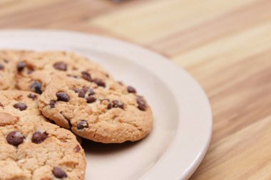Çikolatalı kurabiyeler açık kahverengi bir tabakta hazırlanır ve çocuklara servis edilmeye hazırdır..
