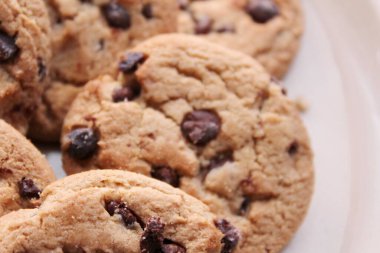 Çikolatalı kurabiyeler açık kahverengi bir tabakta hazırlanır ve çocuklara servis edilmeye hazırdır..