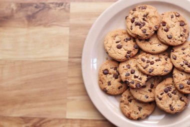 Çikolatalı kurabiyeler açık kahverengi bir tabakta hazırlanır ve çocuklara servis edilmeye hazırdır..