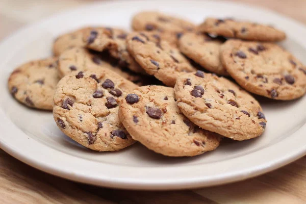 Çikolatalı kurabiyeler açık kahverengi bir tabakta hazırlanır ve çocuklara servis edilmeye hazırdır..