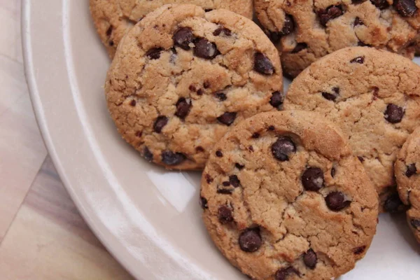 Çikolatalı kurabiyeler açık kahverengi bir tabakta hazırlanır ve çocuklara servis edilmeye hazırdır..