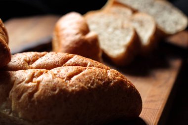 Taze pişmiş ekmek tahta bir kesme tahtasıyla dilimleniyor..