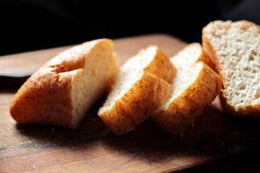 Taze pişmiş ekmek tahta bir kesme tahtasıyla dilimleniyor..