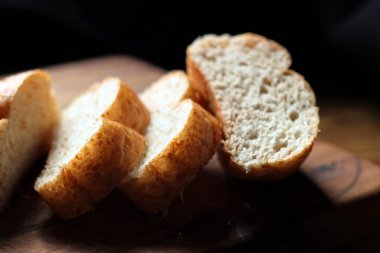 Taze pişmiş ekmek tahta bir kesme tahtasıyla dilimleniyor..