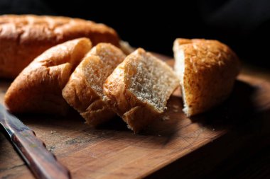 Taze pişmiş ekmek tahta bir kesme tahtasıyla dilimleniyor..