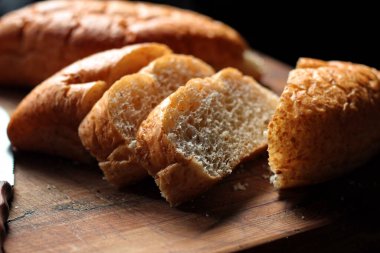 Taze pişmiş ekmek tahta bir kesme tahtasıyla dilimleniyor..