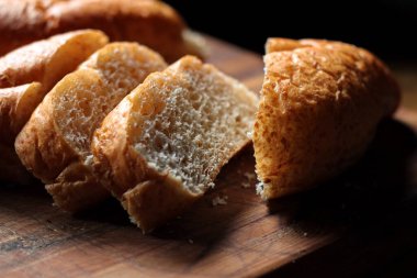 Servise hazır taze buğday bolioları ahşap bir kesme tahtasıyla kesildi..