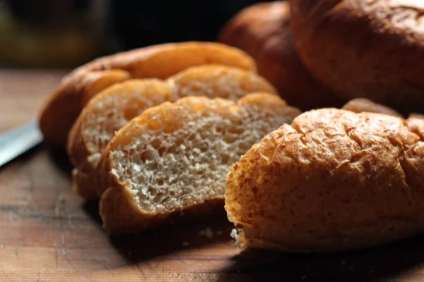 Servise hazır taze buğday bolioları ahşap bir kesme tahtasıyla kesildi..