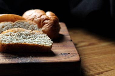 Servise hazır taze buğday bolioları ahşap bir kesme tahtasıyla kesildi..