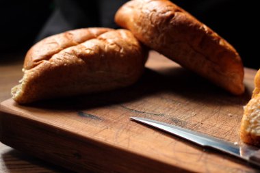 Buğday boliloları ya da taze pişmiş tahıl ekmeği ahşap bir kesme tahtasıyla kesiliyordu..