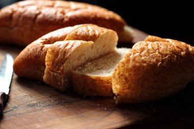 Taze pişmiş ekmek tahta bir kesme tahtasıyla dilimleniyor..