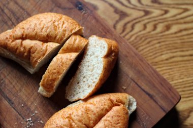 Buğday boliosu veya taze pişmiş kepekli ekmeğin ahşap bir kesim tahtasına dilimlenmesi. Fotoğraf: Düz Düz Düz