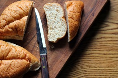 Buğday boliosu veya taze pişmiş kepekli ekmeğin ahşap bir kesim tahtasına dilimlenmesi. Fotoğraf: Düz Düz Düz