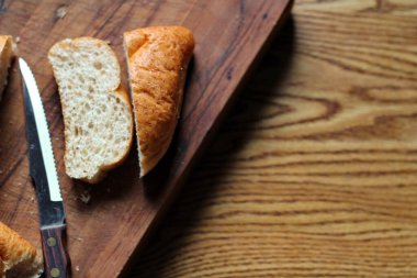 Buğday boliosu veya taze pişmiş kepekli ekmeğin ahşap bir kesim tahtasına dilimlenmesi. Fotoğraf: Düz Düz Düz
