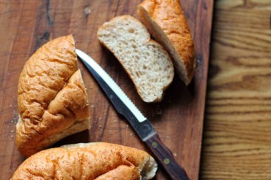 Buğday boliosu veya taze pişmiş kepekli ekmeğin ahşap bir kesim tahtasına dilimlenmesi. Fotoğraf: Düz Düz Düz