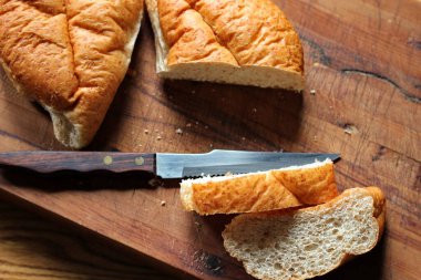 Buğday boliosu veya taze pişmiş kepekli ekmeğin ahşap bir kesim tahtasına dilimlenmesi. Fotoğraf: Düz Düz Düz