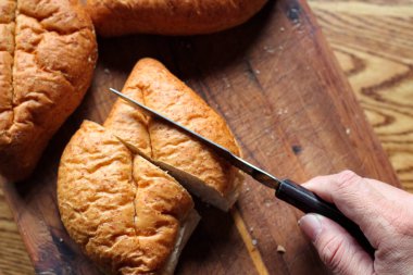 Ekmek tahta bir kesme tahtasıyla dilimleniyor. Taze yapılmış bir ekmek. Fotoğraf: Düz Düz Düz
