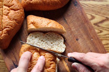Ekmek tahta bir kesme tahtasıyla dilimleniyor. Taze yapılmış bir ekmek. Fotoğraf: Düz Düz Düz
