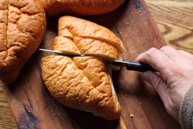 Ekmek tahta bir kesme tahtasıyla dilimleniyor. Taze yapılmış bir ekmek. Fotoğraf: Düz Düz Düz
