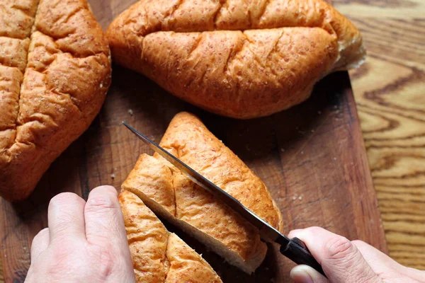 Ekmek tahta bir kesme tahtasıyla dilimleniyor. Taze yapılmış bir ekmek. Fotoğraf: Düz Düz Düz