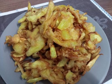 Ahşap bir masada gri bir tabakta sunulan meyveli turta..