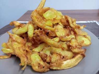 Ahşap bir masada gri bir tabakta sunulan meyveli turta..